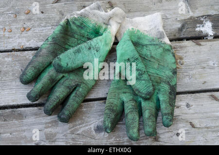 Ein paar alte und gebrauchte grüne Schutzhandschuhe auf Holz Hintergrund Stockfoto