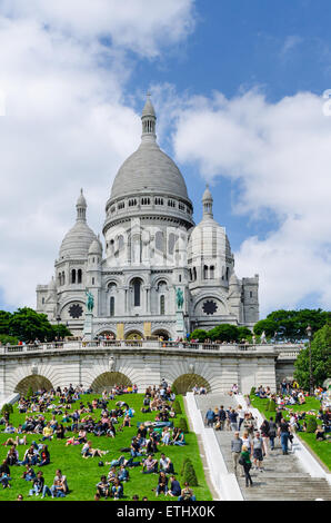 Menschen liegen auf Rasen vor Sacre Coeur Kirche in Paris, Frankreich, vertikal Stockfoto