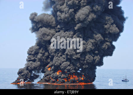 Dunkle Wolken füllen den Himmel so aufräumen Besatzungen Verhalten kontrolliert verbrennt Öl von der Oberfläche des Golfs von Mexiko nach der BP Deepwater Horizon Öl gesammelt zu Katastrophe verschütten als Bemühungen zur Eindämmung und reinigen Sie die Millionen von Gallonen Crew weiter 9. Juni 2010 im Golf von Mexiko. Stockfoto