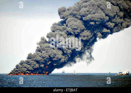 Dunkle Wolken füllen den Himmel wie Krabbenkutter einen Boom verwenden, um Erdöl zu sammeln, während eine kontrollierte Oberfläche brennen nach der BP Deepwater Horizon-Ölkatastrophe als Bemühungen zur Eindämmung und reinigen Sie die Millionen von Gallonen Crew weiter 20. Juni 2010 im Golf von Mexiko. Stockfoto