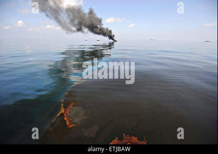 Dunkle Wolken füllen den Himmel so aufräumen Besatzungen Verhalten kontrolliert verbrennt Öl von der Oberfläche des Golfs von Mexiko nach der BP Deepwater Horizon Öl gesammelt zu Katastrophe verschütten als Bemühungen zur Eindämmung und reinigen Sie die Millionen von Gallonen Crew weiter 6. Mai 2010 im Golf von Mexiko. Stockfoto