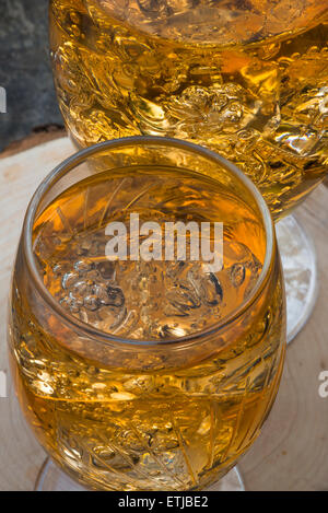Glas kalte erfrischende Apfelschorle mit Eiswürfeln und Äpfel auf Holztisch Stockfoto