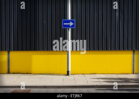 Verkehrsschild, Pfeil rechts gegen gelbe Wand zeigend Stockfoto
