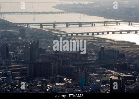 Luftbild vom Umeda Sky Building, Osaka, von Eisenbahn- und Straßenbrücken, die Kyu-Yodo, Yodo, Fluss, bei Sonnenuntergang, goldene Stunde überspannen. Hazy aufgrund von Umweltverschmutzung. Stockfoto