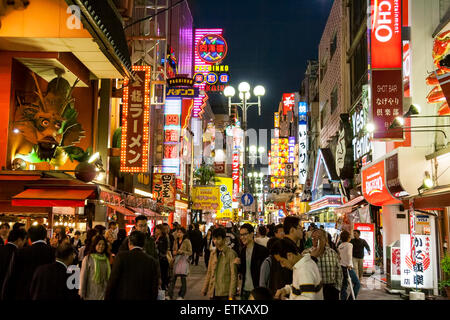 Abends, Kinryu Ramen Restaurant im Vordergrund, dann Blick entlang der beleuchteten Neon-Schilder auf der überfüllten belebten Fußgängerzone in Dotonbori, Osaka. Stockfoto