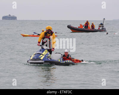 Ein Rettungsschwimmer auf einem Jetski hilft einen Schwimmer, die in Schwierigkeiten stecken, während einer Triathlon-Veranstaltung im Solent Stockfoto