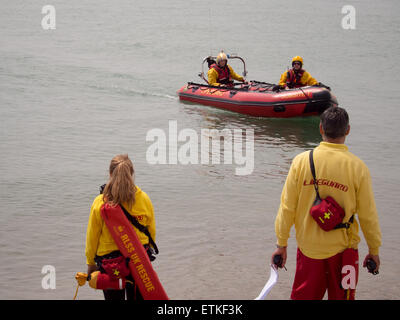 Stehen am Strand und in einer Rippe Rettungsschwimmer wachen über Schwimmer im Meer Stockfoto