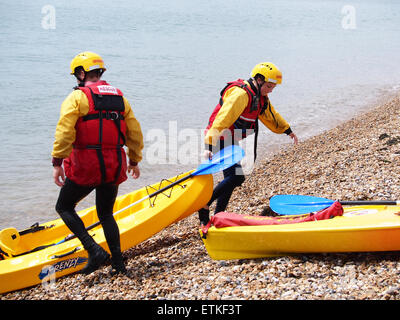 RLSS Rettungsschwimmer ziehen ihre Kajaks auf Southsea Strand, Portsmouth, Hampshire. Stockfoto