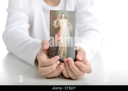 Ein spanischer Junge zeigt ein Bild des Barmherzigen Jesus hielt es mit beiden Händen Stockfoto