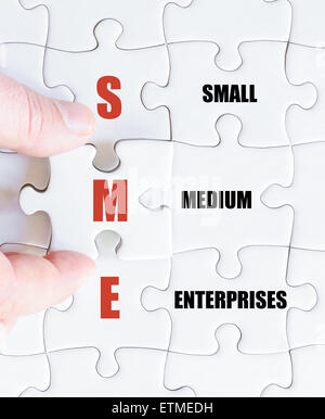Hand of a business man completing the puzzle with the last missing piece.Concept image of Business Acronym SME as Small Medium Enterprises Stockfoto