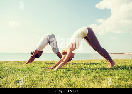 Lächelndes Paar machen Yoga Übungen im Freien Stockfoto