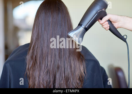 Stylist Hand mit Ventilator trocknet Frau Haare im salon Stockfoto