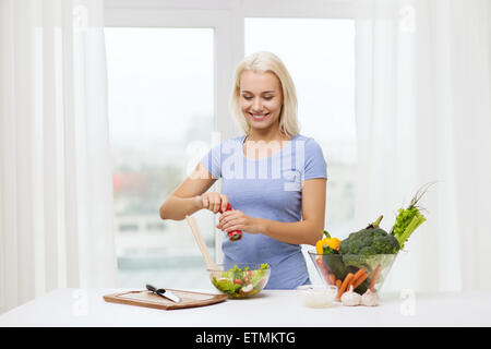 lächelnde Frau Koch Gemüsesalat zu Hause Stockfoto