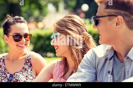 Gruppe von lächelnden Freunde draußen sitzen im park Stockfoto