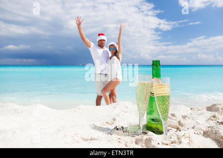 Glückliches Paar feiert Weihnachten mit Sekt am Strand Stockfoto