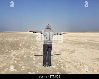 Rückansicht eines Mannes mit ausgestreckten Armen an einem Strand, Fanoe, Jütland, Dänemark Stockfoto