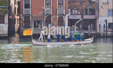 Ein Boot ruderte von sechs Männern und unter der venezianischen Flagge eines geflügelten Löwen bewegt sich entlang des Canal Grande Venedig Veneto Italien Europa Stockfoto