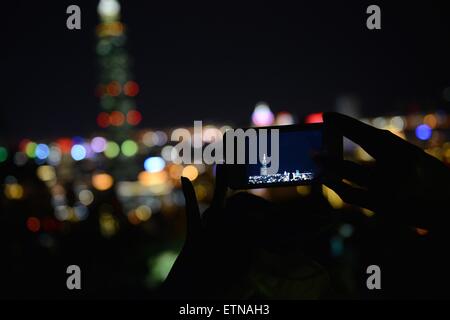 Silhouette einer Person, die ein Mobilgerät hält und ein Foto von Taipei, Taiwan, macht Stockfoto