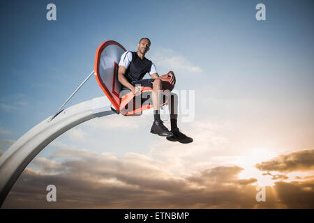 Porträt eines jungen Mannes sitzen in einen Basketballkorb in einem Park, Los Angeles, Kalifornien, USA Stockfoto