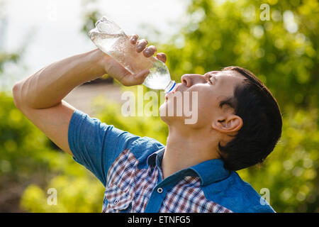 Mann trinkt Wasser aus einer Plastikflasche auf der Straße in die summ Stockfoto
