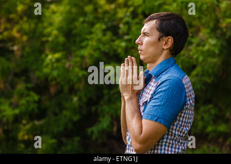 Lassen Sie den Mann auf der Straße, auf einem grünen Hintergrund zu Gott beten Stockfoto