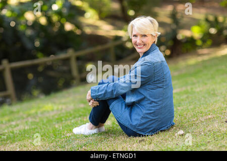 attraktive Mitte Alter Frau sitzen im freien Stockfoto