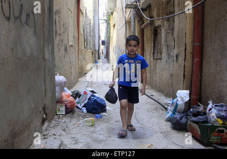 Jerusalem, Jerusalem, Palästina. 14. Juni 2015. Ein palästinensischer Jugendlicher geht vorbei an angesammelten Müllberge in die palästinensischen Flüchtlingslager Schuafat in Ost-Jerusalem, am 14. Juni 2015. Das Flüchtlingslager ist mit Abfällen überschwemmt, weil UNRWA (United Nations Relief and Works Agency für Palästina-Flüchtlinge im Nahen Osten) und die Gemeinde von Jerusalem, die sanitären Einrichtungen verantworten, t sammeln Abfall fast einen Monat lang Haven © Saeb Awad/APA Bilder/ZUMA Draht/Alamy Live News Stockfoto