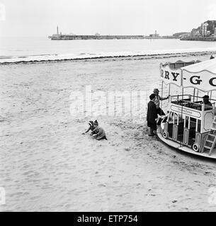 Szenen in Margate, Kent, während der Karfreitag. Zwei Kleinkinder spielen am Strand neben einem Karussell. 27. März 1964. Stockfoto