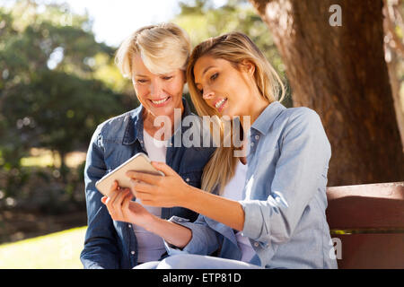 schöne junge Tochter Mitte Alter Smartphone mit Mutter im freien Stockfoto