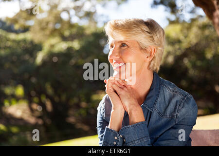 attraktive mittlere gealterte Frau sitzen im park Stockfoto