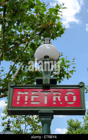 Traditionelle Paris Metro Schild um Bäume mit blauen Wolkenhimmel Stockfoto