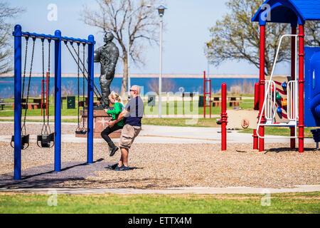 Kaukasische Vater schwingt seine 10 jährige Tochter auf einem öffentlichen Spielplatz in Oklahoma City, Oklahoma, USA. Stockfoto