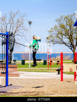 Eine zehn Jahre alte blonde kaukasische Mädchen schwebt hoch auf einer öffentlichen Park-Schaukel. Stockfoto