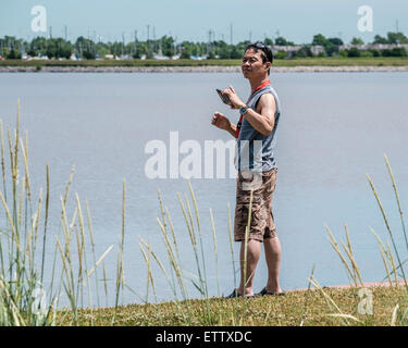 Ein 50 Jahre alter asiatischer Mann nimmt Bilder mit seinem Handy am Lake Hefner in Oklahoma City, Oklahoma, USA. Stockfoto