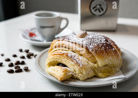 Schoko-Croissant mit Kaffee, Kaffee-Bohnen, die auf der Seite. Stockfoto