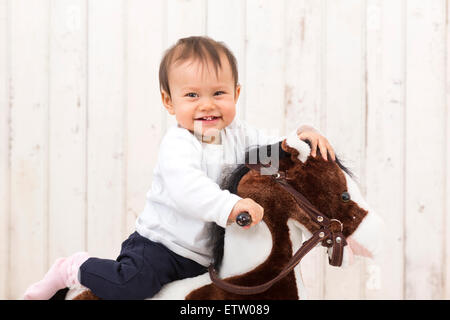 Kleines Mädchen sitzt auf Schaukelpferd lachen Stockfoto