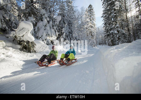 Deutschland, Bayern, Inzell, Paare, die Spaß am Schlitten im tief verschneiten Landschaft Stockfoto