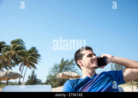 Junger Mann mit Handy am Strand Stockfoto