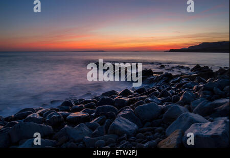 Sonnenuntergang mit nassen Felsvorsprung in der Bucht mit orangefarbenen Himmel Stockfoto