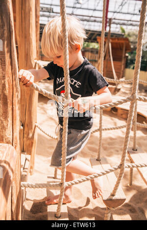 Kleiner Junge Hängebrücke Holzschiff am Spielplatz entlang Stockfoto