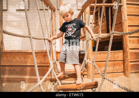 Kleiner Junge Hängebrücke Holzschiff am Spielplatz entlang Stockfoto