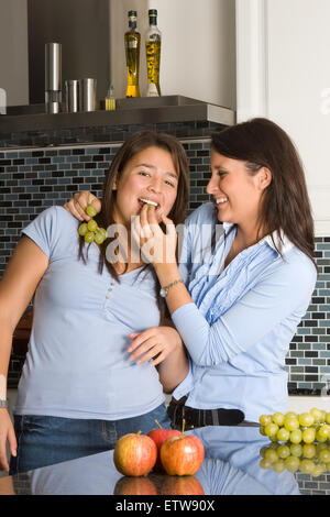 Zwei Freunde, die Spaß in der Küche und schmecken Trauben Stockfoto