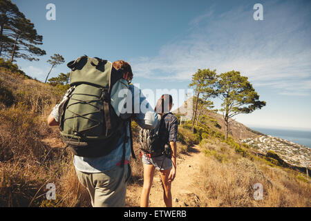 Ansicht von hinten von zwei jungen Menschen zu Fuß auf den Trail Weg am Berg. Junges Paar mit Rucksack wandern. Stockfoto