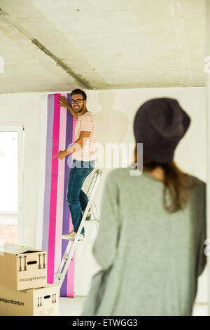 Junger Mann renovieren mit Tapete, Frau Stockfoto