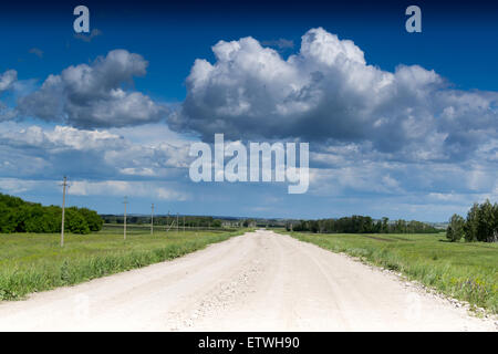 Leere unbefestigte Straße führt in den Horizont wie weiße über Kopf Wolken Stockfoto