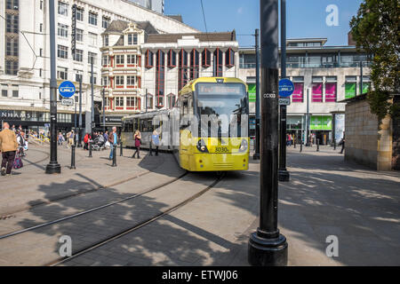 Moderne elektrische Straßenbahn-System läuft durch die Straßen von Manchester, mit Fußgängern sehr nahe an den Bahnlinien Stockfoto