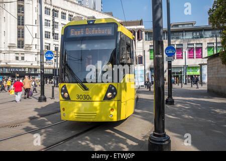 Moderne elektrische Straßenbahn-System läuft durch die Straßen von Manchester, mit Fußgängern sehr nahe an den Bahnlinien Stockfoto