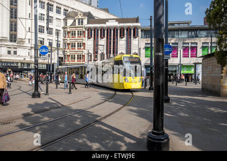 Moderne elektrische Straßenbahn-System läuft durch die Straßen von Manchester, mit Fußgängern sehr nahe an den Bahnlinien Stockfoto