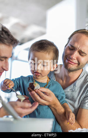 Gay paar backen Kuchen mit Sohn Stockfoto