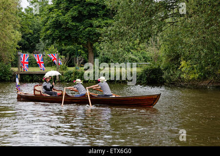 Auf der Themse bei Runnymede ist eine Frau mit Sonnenschirm flussabwärts gerudert. Stockfoto